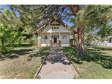 Charming white two-story home with front porch and walkway to the front door surrounded by mature trees at 7801 Valley View St, Louviers, CO 80131
