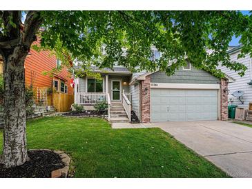 Charming home with a well-maintained lawn, tree, and covered front porch at 12261 N Holly Way, Brighton, CO 80602
