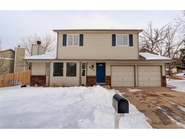 Charming two-story home with a blue door and a two car garage, complemented by a snow-covered front yard at 8012 S Cedar St, Littleton, CO 80120