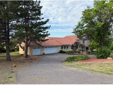 Charming home with a spacious driveway and attached two-car garage, framed by mature trees and a well-manicured lawn at 17852 E Long Ave, Centennial, CO 80016