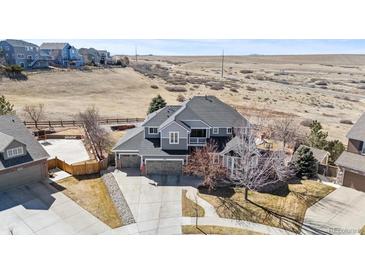 Stunning two-story gray home boasts an attached three-car garage and beautiful landscaping at 12092 S Great Plain Ct, Parker, CO 80134