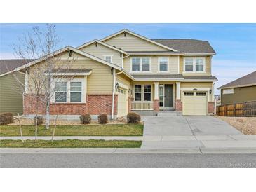 Charming two-story home with tan siding, brick accents, attached garage, and well-manicured lawn on a sunny day at 10052 Isle St, Parker, CO 80134