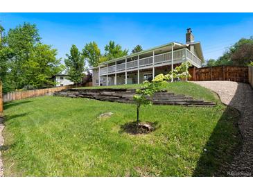 Expansive backyard with lush lawn, terraced retaining wall, and covered back porch at 1420 W Ridge Rd, Littleton, CO 80120