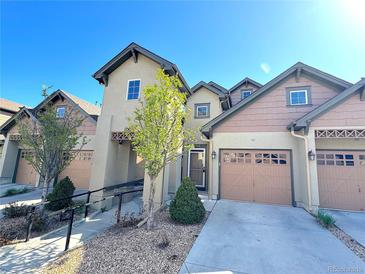 Inviting townhome with a two-car garage and a manicured front yard with decorative trees and bushes at 11983 W Long Cir # 203, Littleton, CO 80127