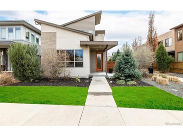Modern home with unique architecture, fresh green lawn, and pathway to the bright orange front door at 1848 W 68Th Ave, Denver, CO 80221
