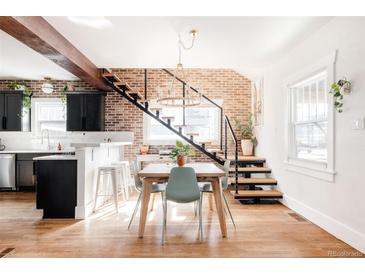 Bright dining room features brick wall, modern light fixture, floating stairs and wood floors at 4452 Stuart St, Denver, CO 80212