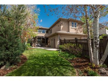 Beautiful backyard with green lawn, mature trees, and patio seating area, ideal for relaxation at 9266 E 35Th Ave, Denver, CO 80238
