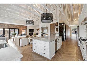 Bright, open-concept kitchen with island, flowing into an inviting living room with high ceilings and exposed beams at 1140 Lake Gulch Rd, Castle Rock, CO 80104