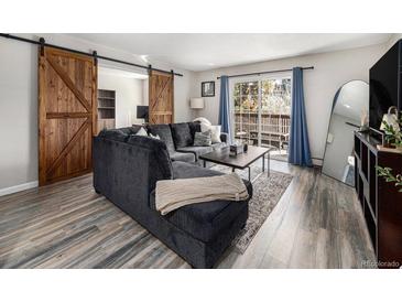 Inviting living room featuring a sectional sofa, sliding barn doors, and access to a private balcony at 6930 E Girard Ave # 304, Denver, CO 80224