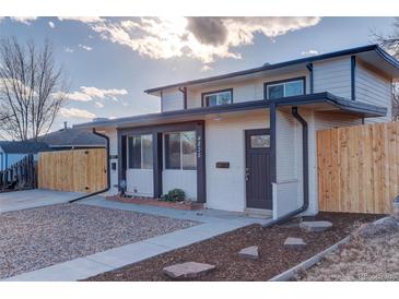 Charming two-story home featuring a fresh white exterior with black trim and a well-maintained front yard at 4835 Grove St, Denver, CO 80221