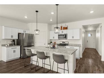 Bright kitchen features stainless appliances, granite counters, and a convenient island with barstool seating at 2326 Monte Vista St, Fort Lupton, CO 80621