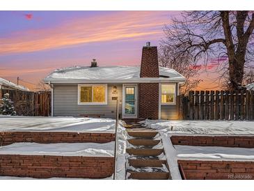 Charming bungalow exterior, snow covered landscaping, brick chimney, and warm sunset at 4820 Newton St, Denver, CO 80221