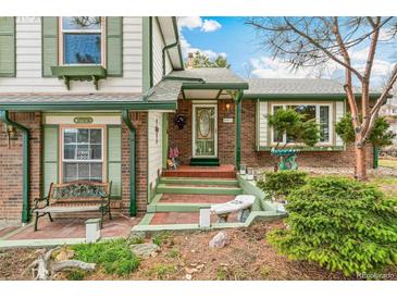 Charming front entrance with brick accents, green trim, and a welcoming doorway and landscaped front yard at 7681 S Jellison St, Littleton, CO 80127