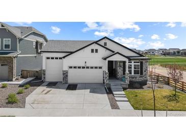 Beautifully designed home featuring a three car garage, stone accents, and manicured lawn at 16218 E 111Th Pl, Commerce City, CO 80022