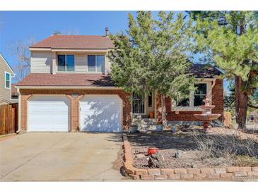 Charming two-story home with a brick facade, two-car garage, mature trees, and manicured landscaping at 15099 E Wagontrail Pl, Aurora, CO 80015