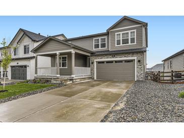 Charming two-story home with a covered porch, stone accents, and a two-car garage at 1420 E Witherspoon Dr, Elizabeth, CO 80107