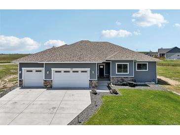 Charming single-story home featuring a three-car garage and manicured lawn at 1180 Antelope W Dr, Bennett, CO 80102