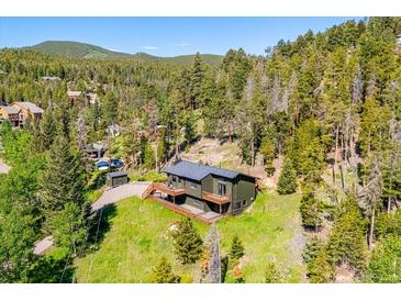 Stunning mountain home with a beautiful deck, surrounded by lush greenery and a scenic hillside at 34075 Grouse Ln, Evergreen, CO 80439