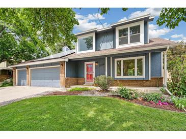 Charming two-story home with a well-manicured lawn, brick accents, and colorful flower beds at 13701 Yank Way, Arvada, CO 80004