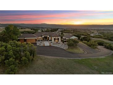 Luxury home with circular driveway, mountain views, and sunset at 1708 Creedmoor Ct, Castle Rock, CO 80109