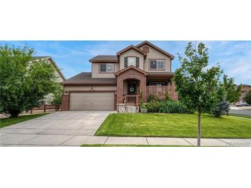 Charming two-story home featuring a brick facade, well-manicured lawn, and inviting covered porch at 19382 Dunraven St, Parker, CO 80134