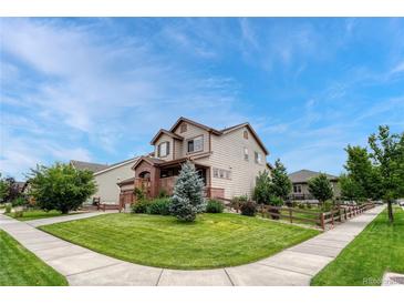 Charming two-story home with a manicured lawn, brick accents, and a welcoming front porch on a sunny day at 19382 Dunraven St, Parker, CO 80134