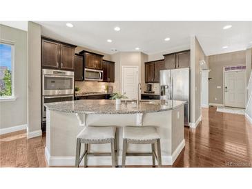 Well-equipped kitchen with dark cabinetry, stainless steel appliances, and a large island with seating at 19382 Dunraven St, Parker, CO 80134