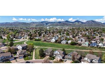 Expansive aerial view showcases a neighborhood surrounded by lush greenery and mountains in the background at 11191 W Crestline Dr, Littleton, CO 80127
