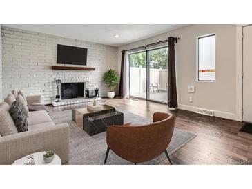 Bright living room features a white brick fireplace, hardwood floors, and sliding door access to outdoor space at 9605 E Kansas Cir # 53, Denver, CO 80247