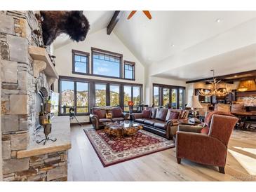 Bright living room features vaulted ceiling, large windows with mountain views, and stone fireplace at 1279 Estates Dr, Breckenridge, CO 80424