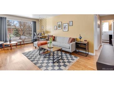 Comfortable living room features a couch, area rug, large window, and an office area, bathed in natural light at 1375 N Williams St # 206, Denver, CO 80218