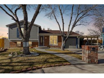 Brick ranch home with gray siding, landscaped yard, and attached garage at 16357 E Wyoming Dr, Aurora, CO 80017