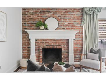 Living room featuring a brick fireplace with white mantle and round mirror at 700 N Washington St # 502, Denver, CO 80203