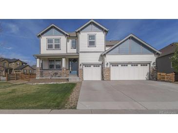 Charming two-story home features a three-car garage, covered porch, and manicured front lawn at 404 Dusk Ct, Erie, CO 80516