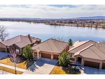 Stunning aerial view of lakeside homes with tile roofs and beautiful landscaping on a sunny day at 7700 W Grand Ave, Littleton, CO 80123