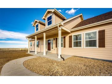 Charming two-story home featuring a welcoming front porch with stone and manicured landscaping at 4820 S County Road 137, Bennett, CO 80102