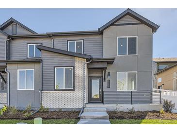 Two-story townhome with gray siding, brick accents, and a modern front entrance at 1242 S Algonquian, Aurora, CO 80018