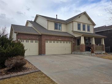 Charming two-story home with a brick and tan exterior, spacious driveway, and inviting front porch at 13018 Niagara Way, Thornton, CO 80602