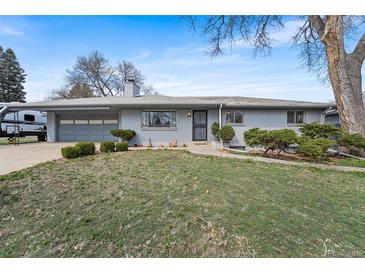 Charming single-story home with a gray painted brick, attached garage, and neatly manicured front lawn at 415 Lamar St, Lakewood, CO 80226