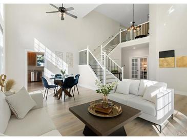 Bright, open living room with soaring ceilings, dining area, and modern staircase at 2089 Meadow Sweet Ln, Erie, CO 80516