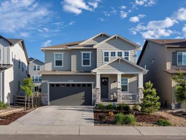 Charming two-story home with gray siding, covered porch, landscaped yard, and attached two-car garage at 8354 Big Thompson St, Littleton, CO 80125