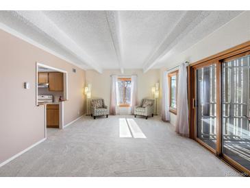 Bright living room features a beamed ceiling, large windows, and sliding door access to the outdoors at 2525 S Dayton Way # 1514, Denver, CO 80231