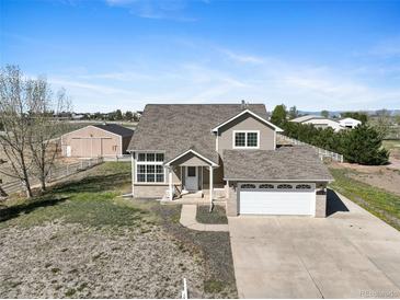 Charming two-story home with a spacious yard, complemented by an attached two-car garage and barn in the background at 16275 Electra St, Brighton, CO 80603