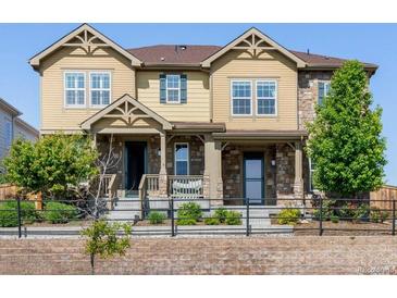 Charming tan townhouse with stone accents, well-kept landscaping and a cozy, covered front porch at 23293 E Jamison Dr, Aurora, CO 80016