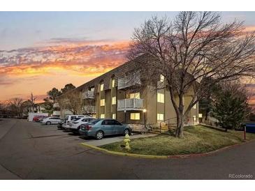 Apartment building exterior at dusk with parking lot and landscaping at 7455 E Quincy Ave # 101, Denver, CO 80237