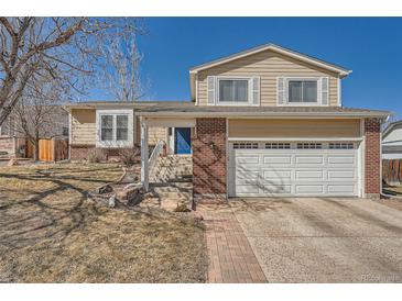 Charming two-story home with brick accents, attached garage, and landscaped front yard under a clear blue sky at 18347 E Nassau Dr, Aurora, CO 80013