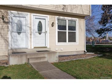 Charming townhouse featuring well-maintained front entrance with a decorative door and a green lawn at 3121 S Estes St, Lakewood, CO 80227