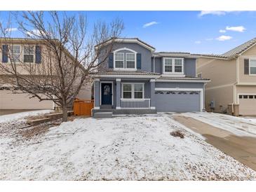 Charming two-story home with a covered front porch, shutters, and a two-car garage on a snow covered lot at 1963 Hogan Ct, Castle Rock, CO 80109