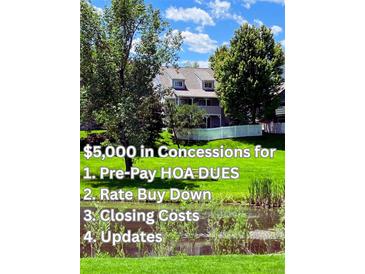 Beautiful townhome with a white picket fence surrounded by lush green grass, trees, and a pond at 10433 Red Mountain W, Littleton, CO 80127