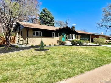 Charming ranch home featuring a well-manicured lawn and a bright turquoise front door at 5563 E Jefferson Ave, Denver, CO 80237